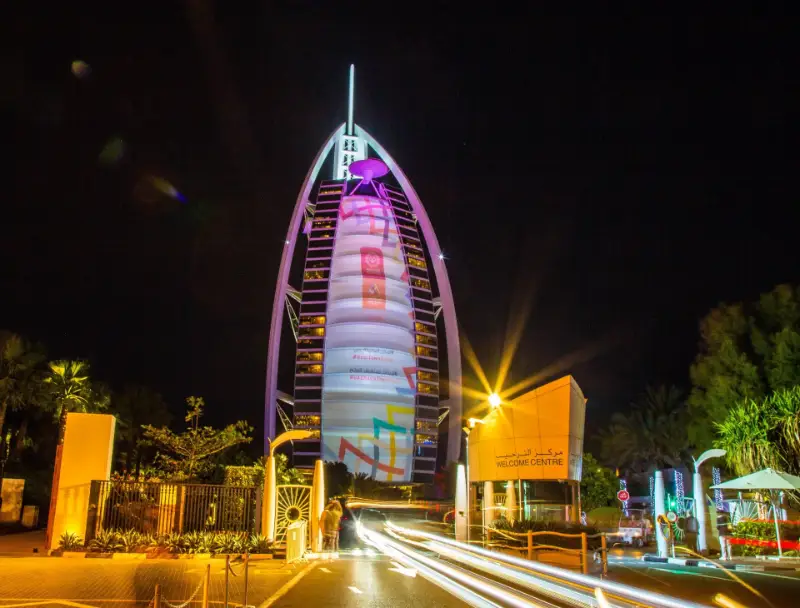Burj Al Arab illuminated at night above the Welcome Centre gate